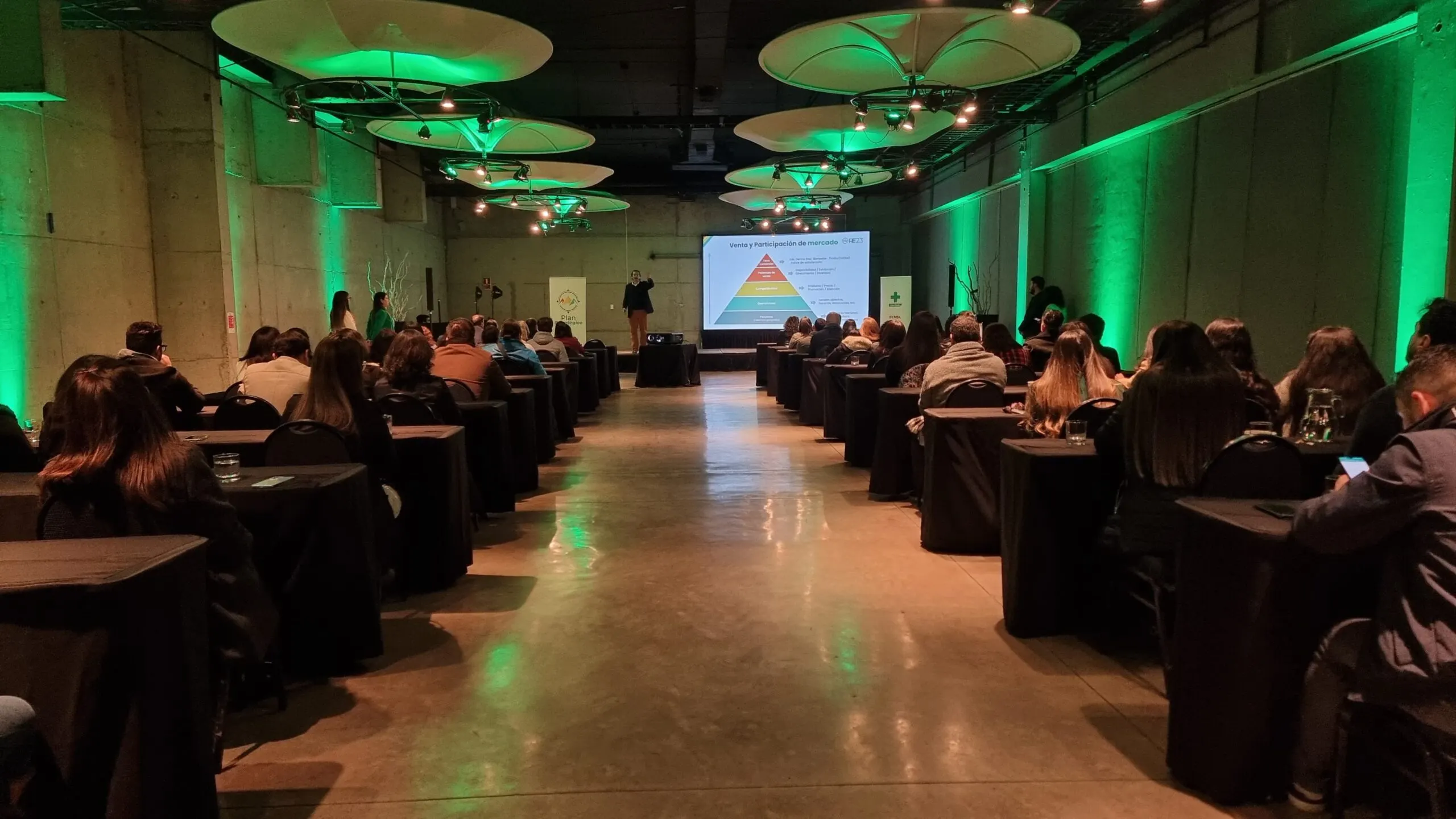 Auditorio con filas de asistentes e iluminación verde